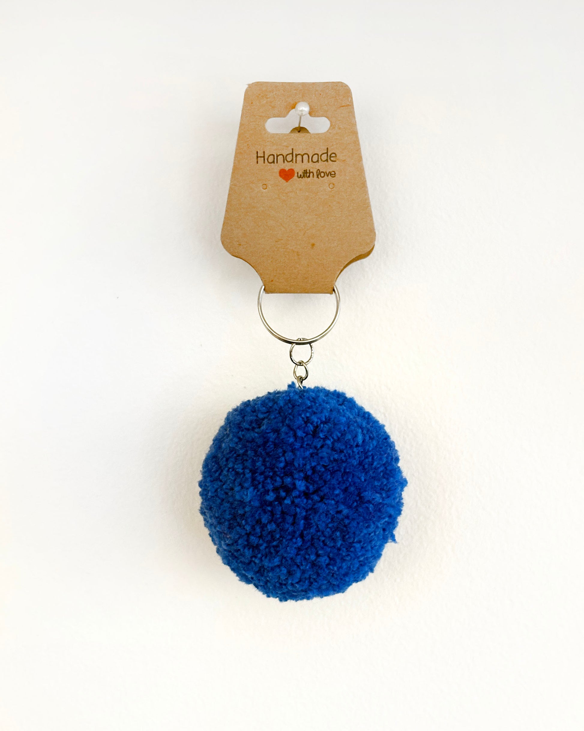 Pom pom obesek temno modre barve.
