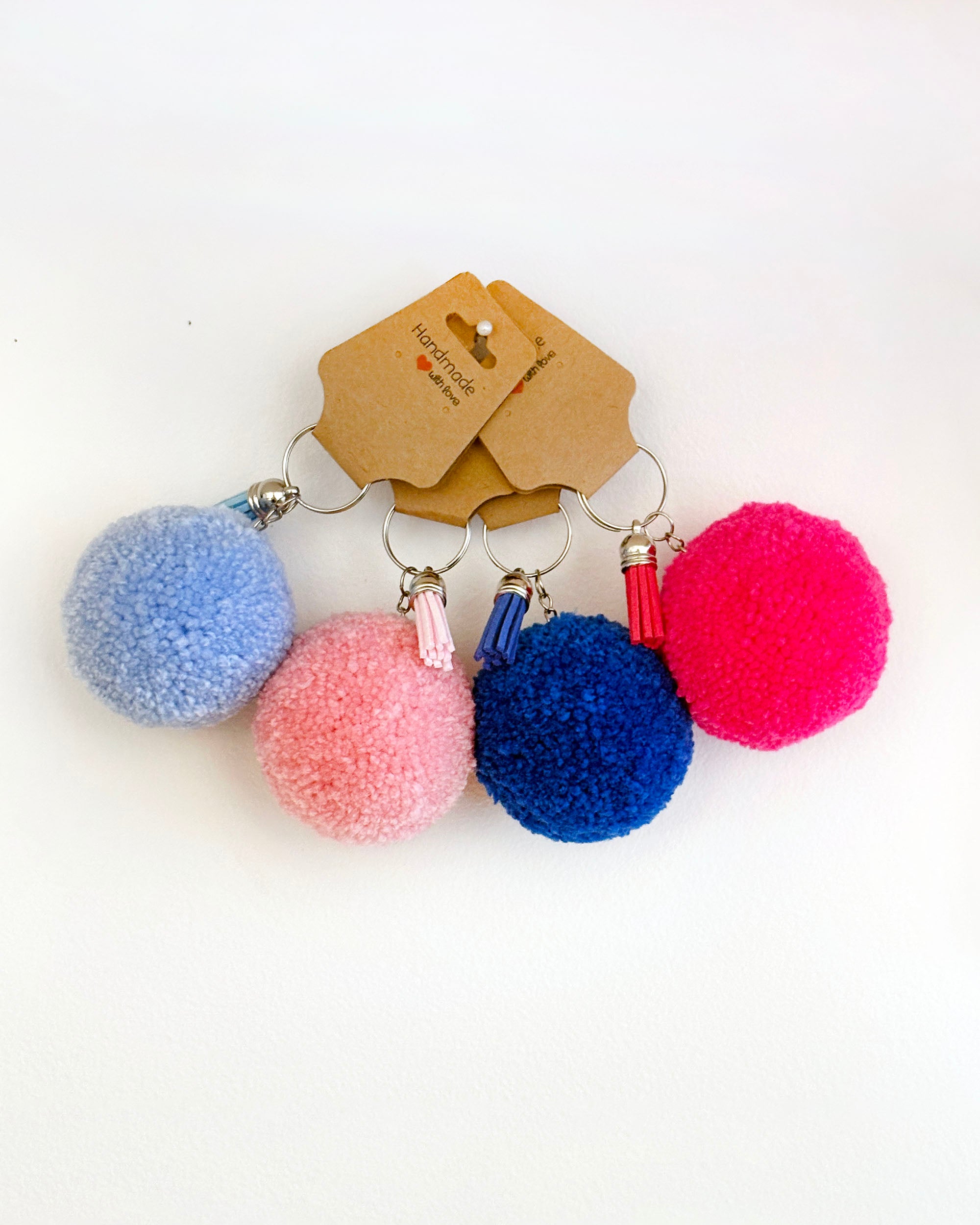 Pom pom obeski v svetlo modri, temno modri, roza barvi ter v barvi fuksije, z resico.
