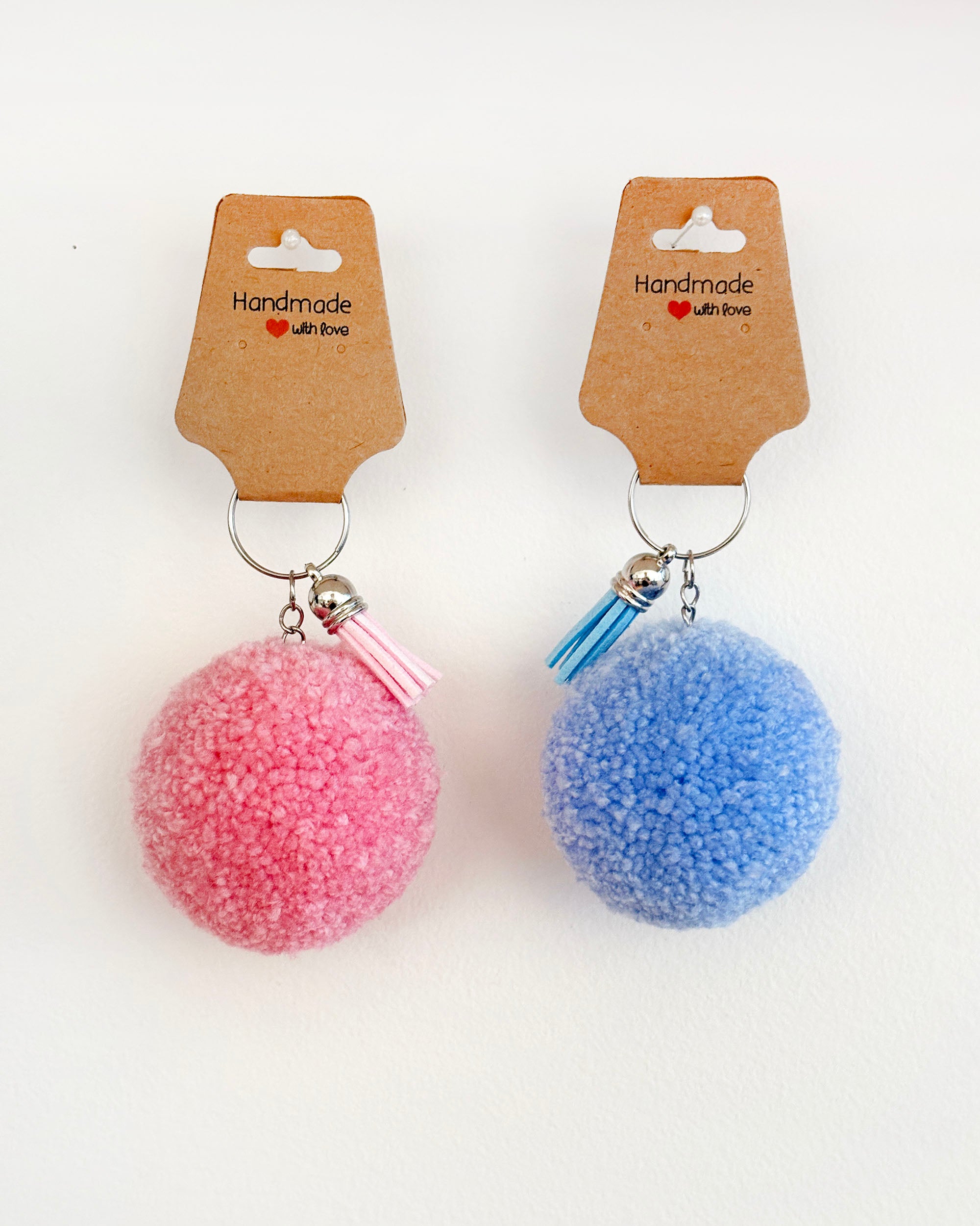 Pom pom obesek v roza in temno modri barvi z resico.
