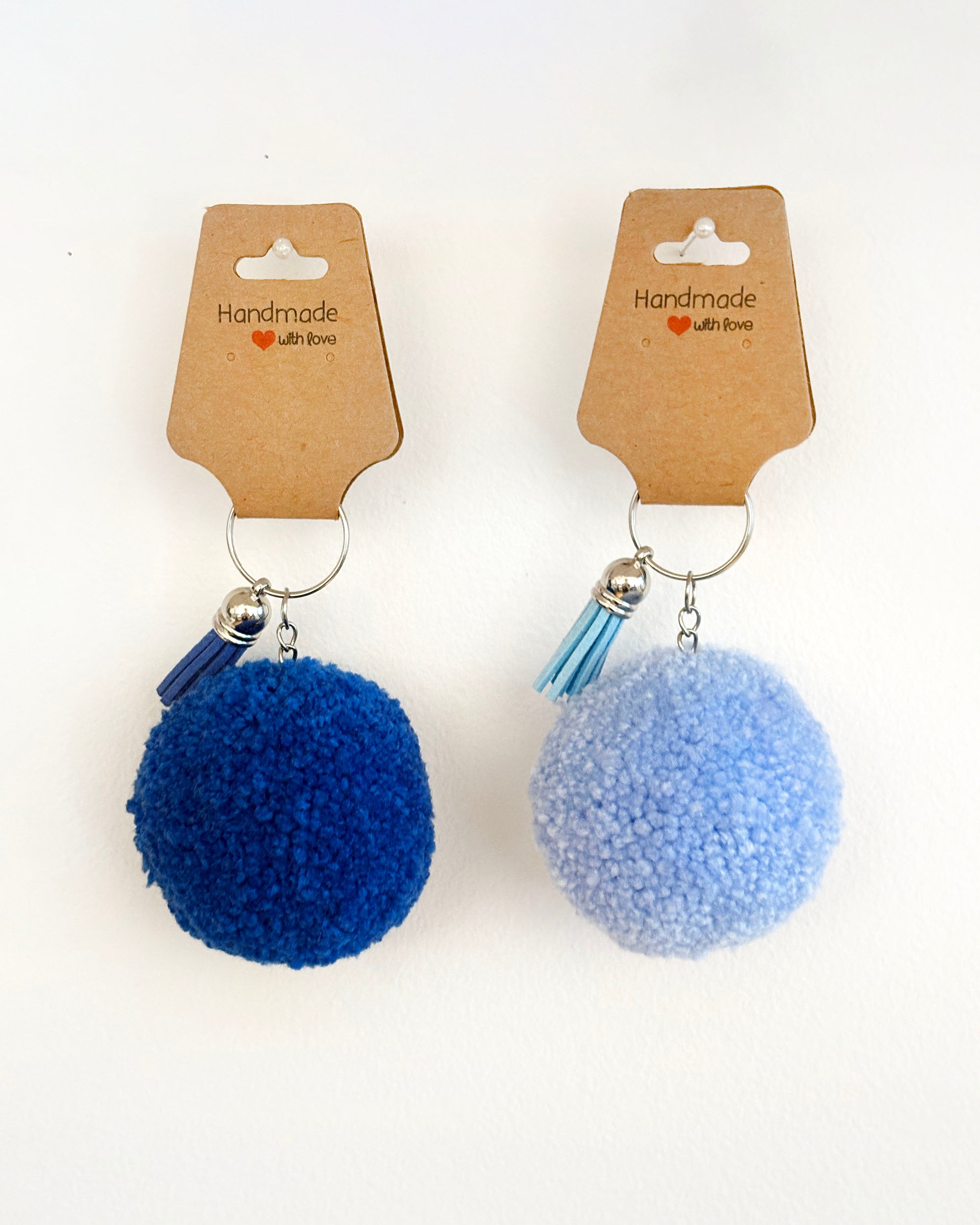 Pom pom obesek v temno modri in svetlo modri barvi z resico.
