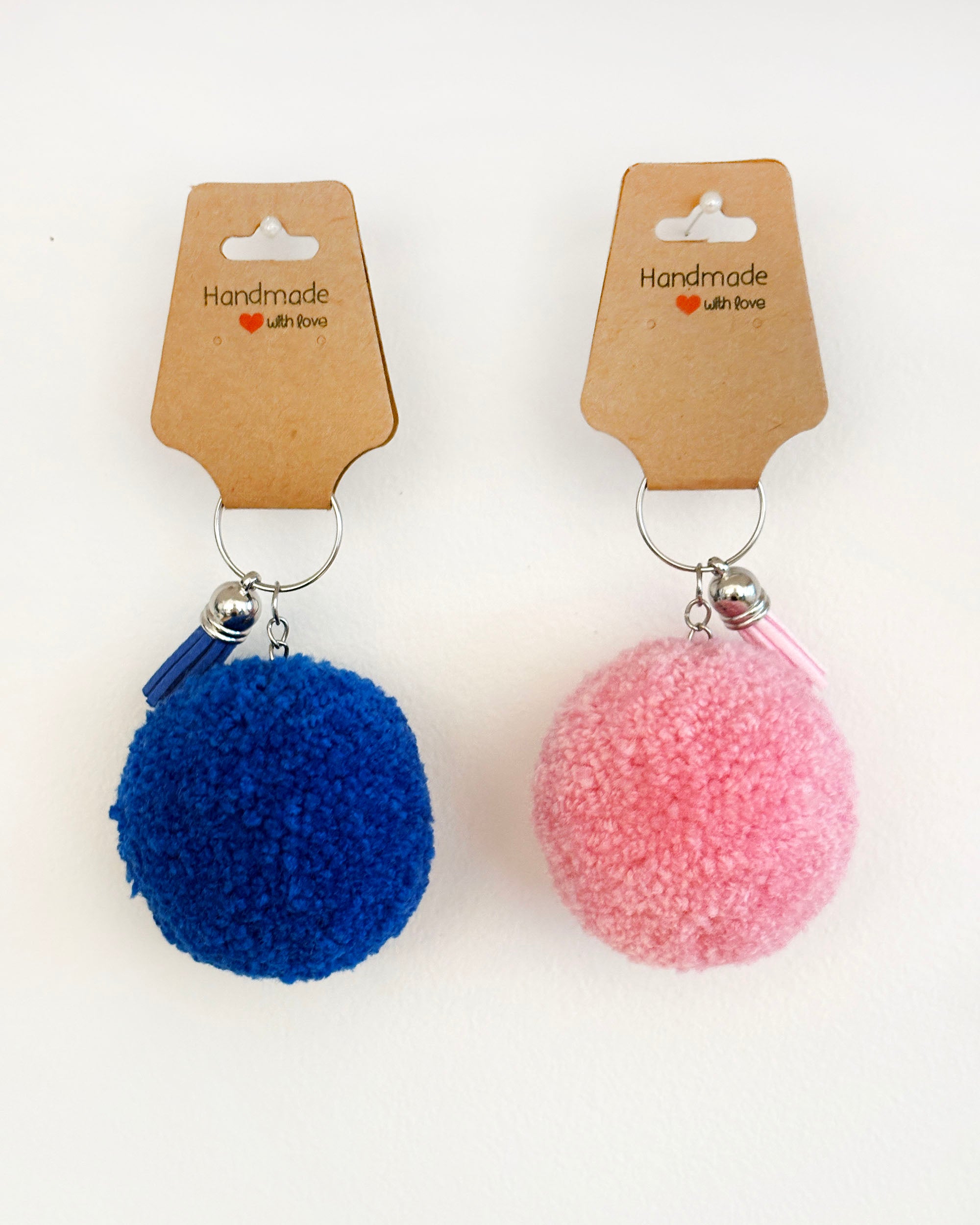 Pom pom obesek v temno modri in roza barvi z resico.
