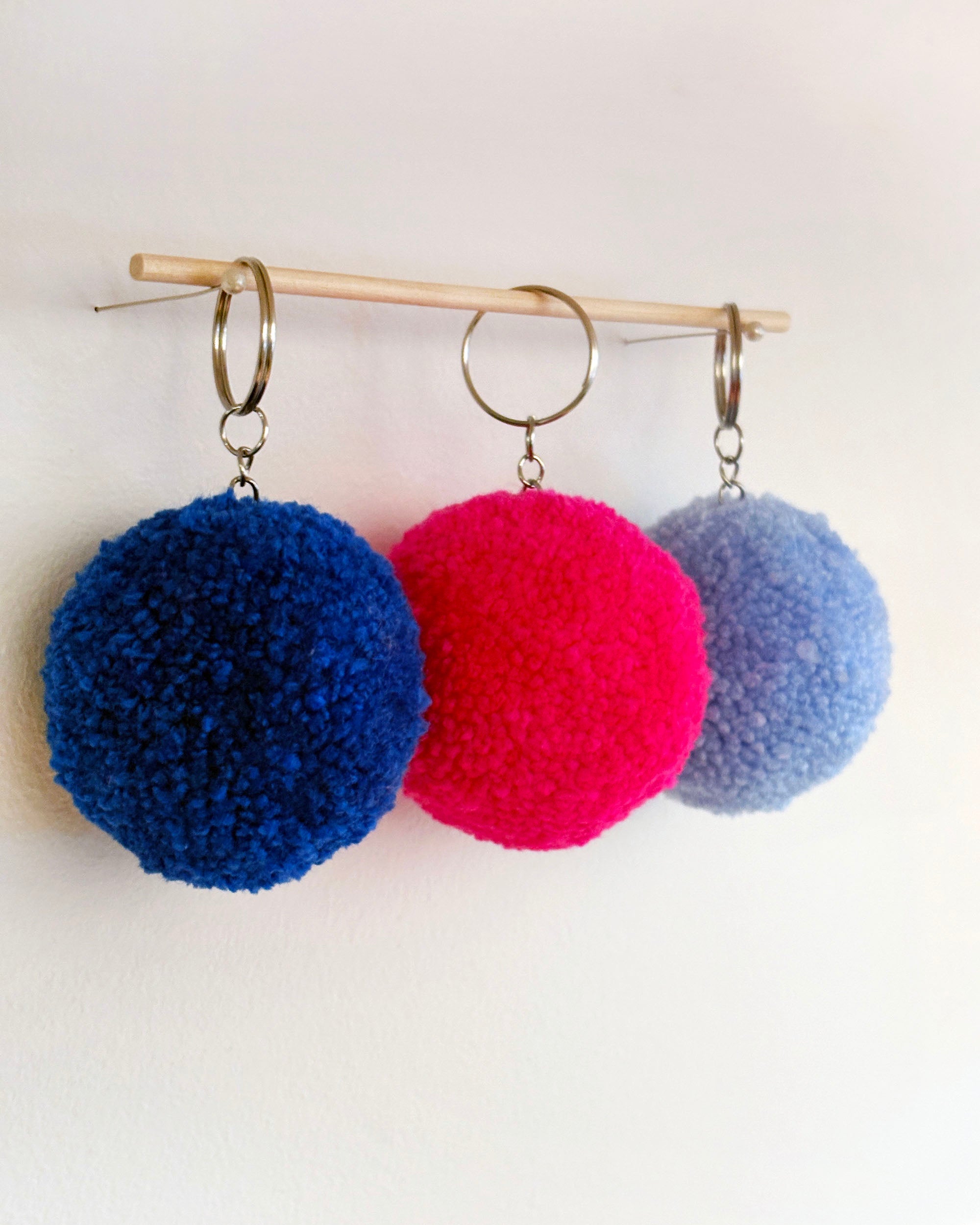 Pom pom obeski temno modre, svetlo modre barve ter v barvi fuksija.