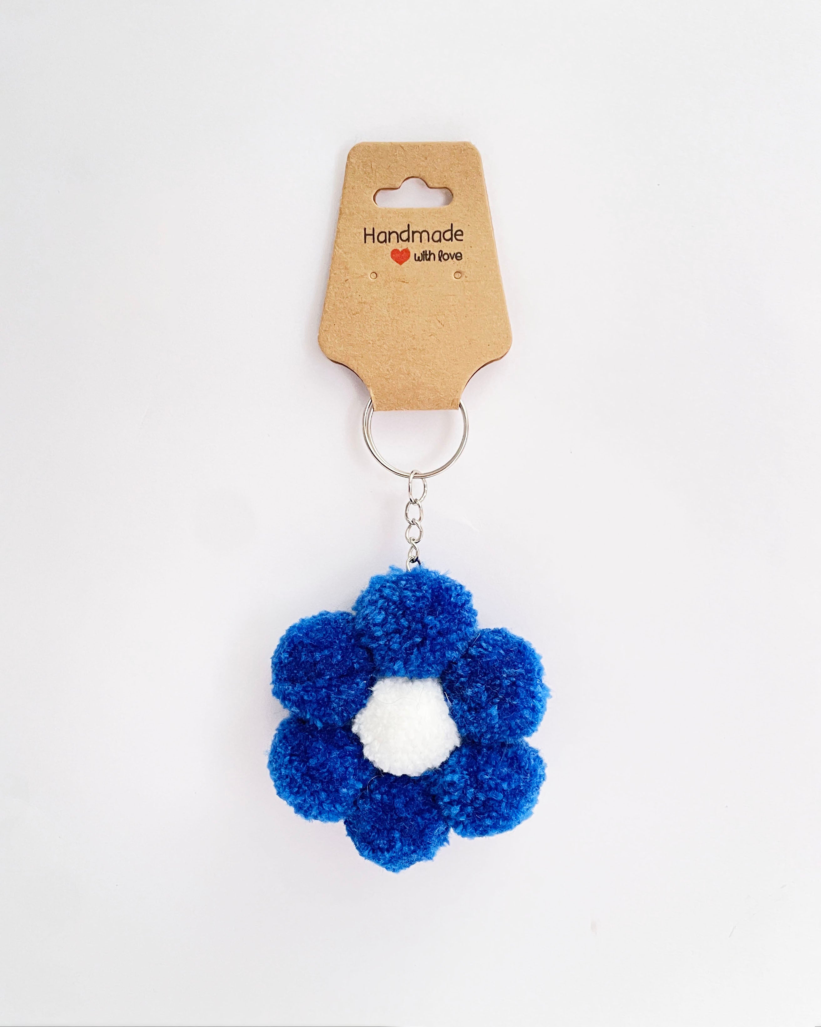 Pom pom obesek za kljuce, nahrbtnik, torbo v temno moedri barvi v obliki rožice.