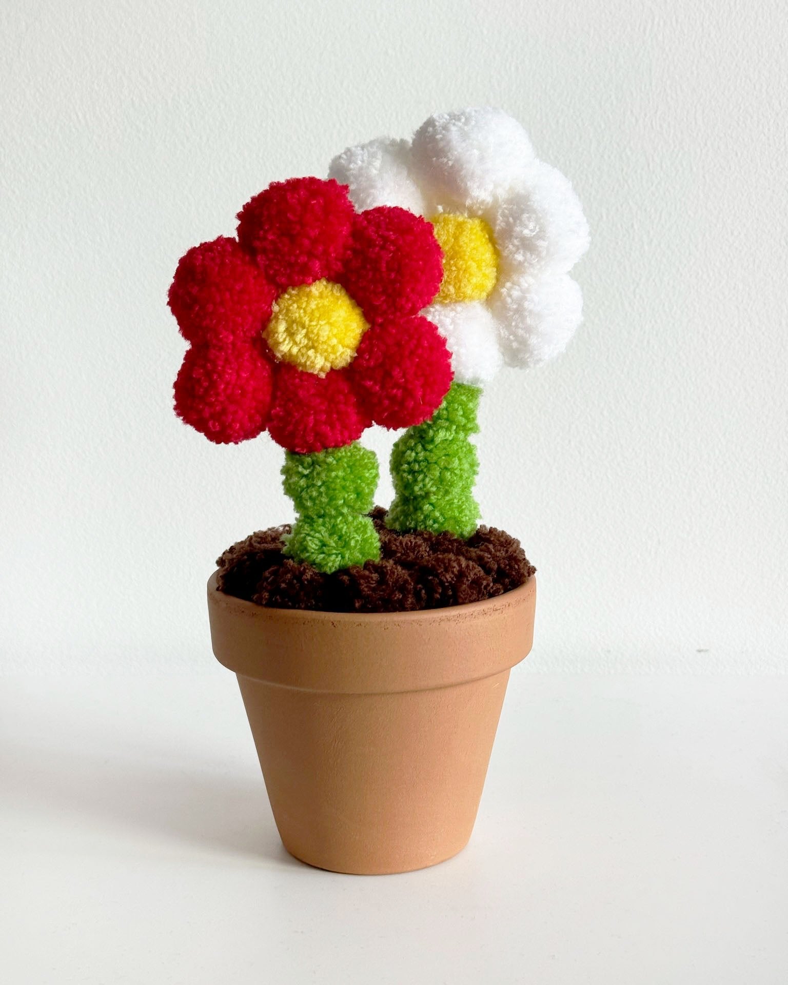 Pom pom roža iz cofov, glinen lonček, na mizi