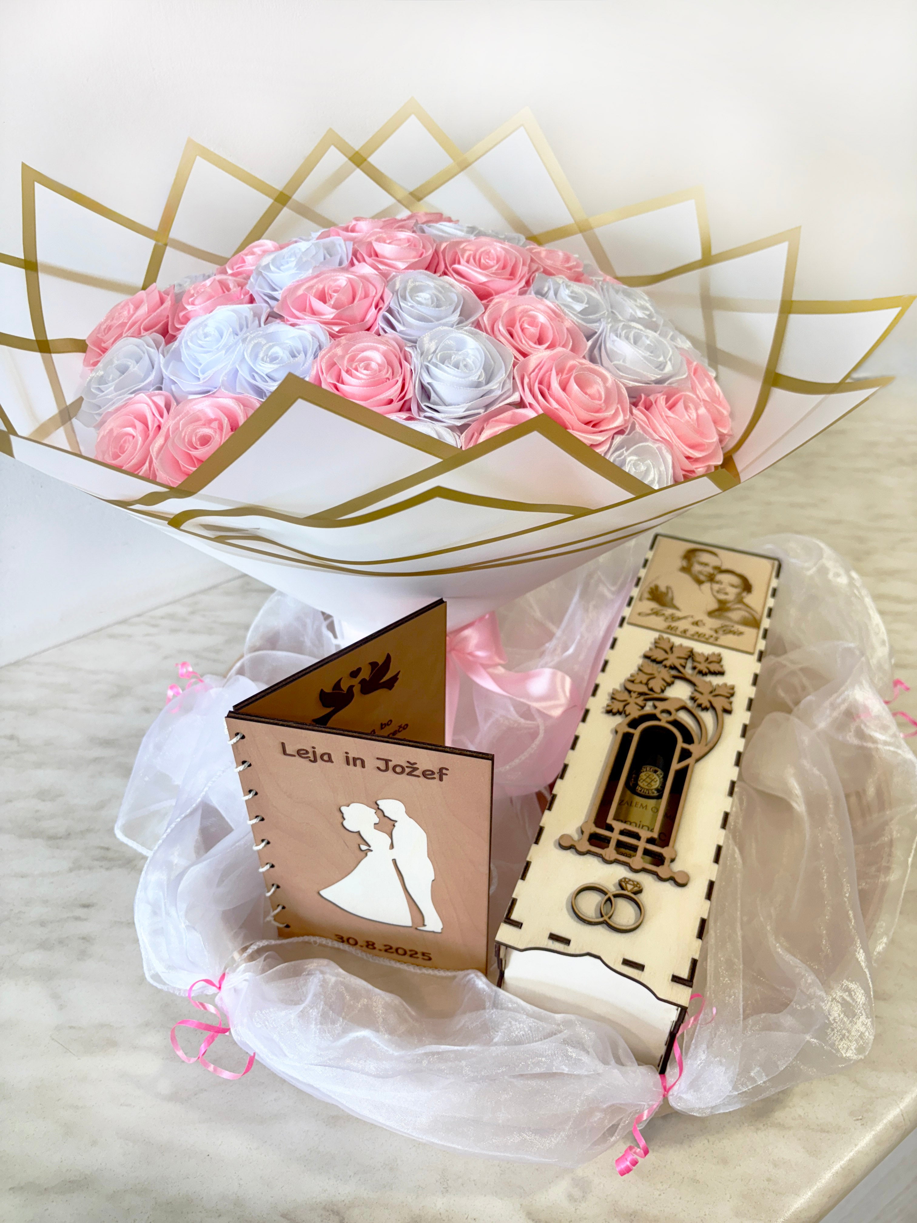 Satenast šopek svetlo roza in bele barve, zavit v bel korejski papir, z leseno čestitko in škatlo za vino hoplales