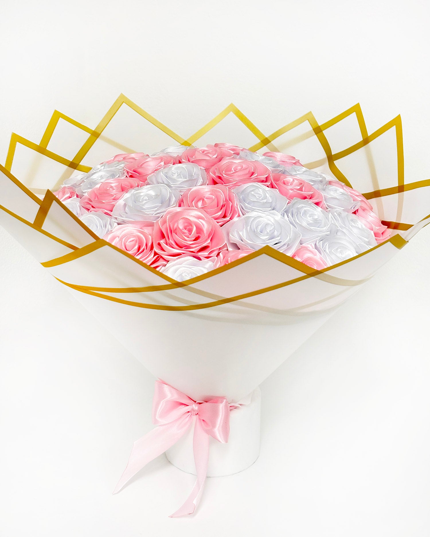 Satenast šopek v beli in svetlo roza barvi, zavit v bel eleganten korejski papir, z zlatim robom. Slikan od spredaj, z roza pentljo.