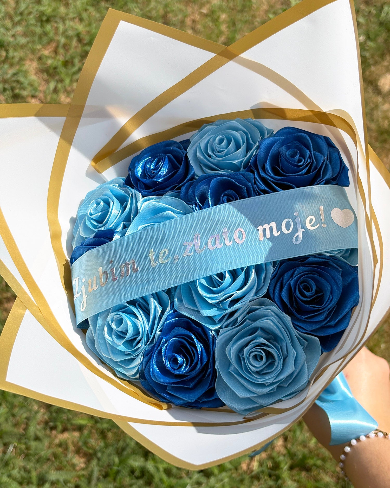 Satenas šopek, v barvah svetlo in temno modre, vrtnice, zavite v bel korejski papir, z napisom ljubim te zlato moje.