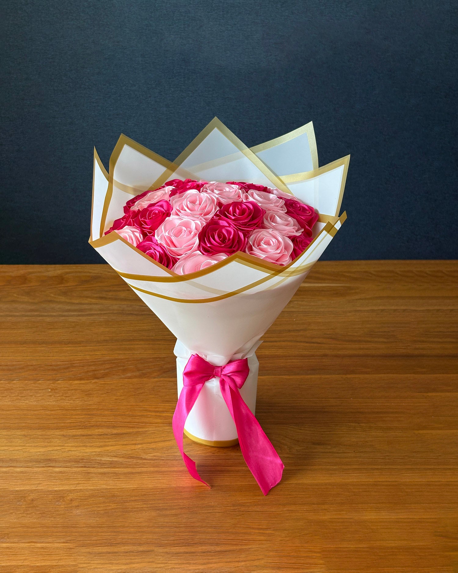 Satenast šopek vrtnic v svetlo roza in temno roza barvi, na mizi
