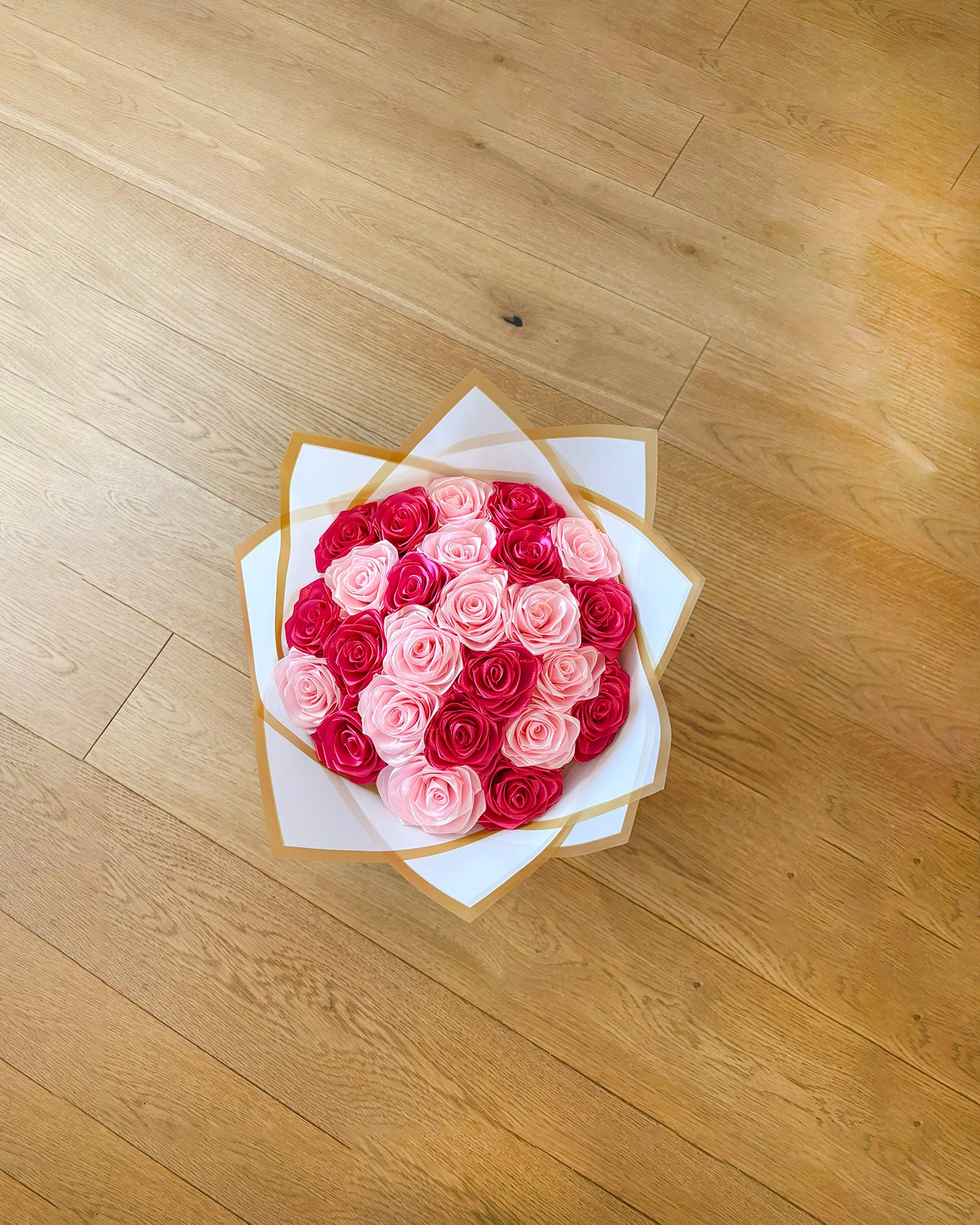 Satenast šopek vrtnic v svetlo roza in temno roza barvi slikan od zgoraj
