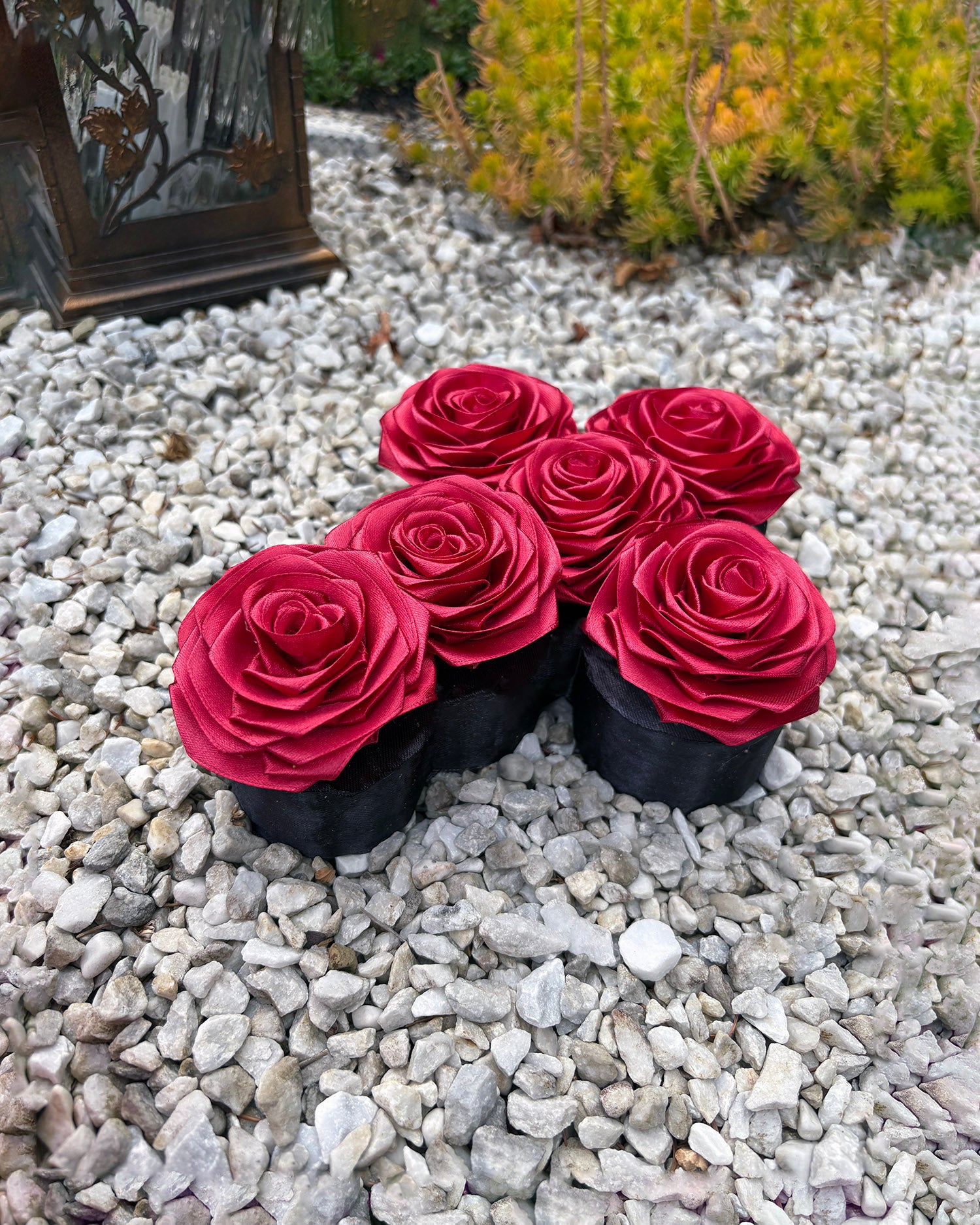 Križ iz satenastih vrtnic, v bordo rdeči barvi, trajen spomin, slikan na grobu