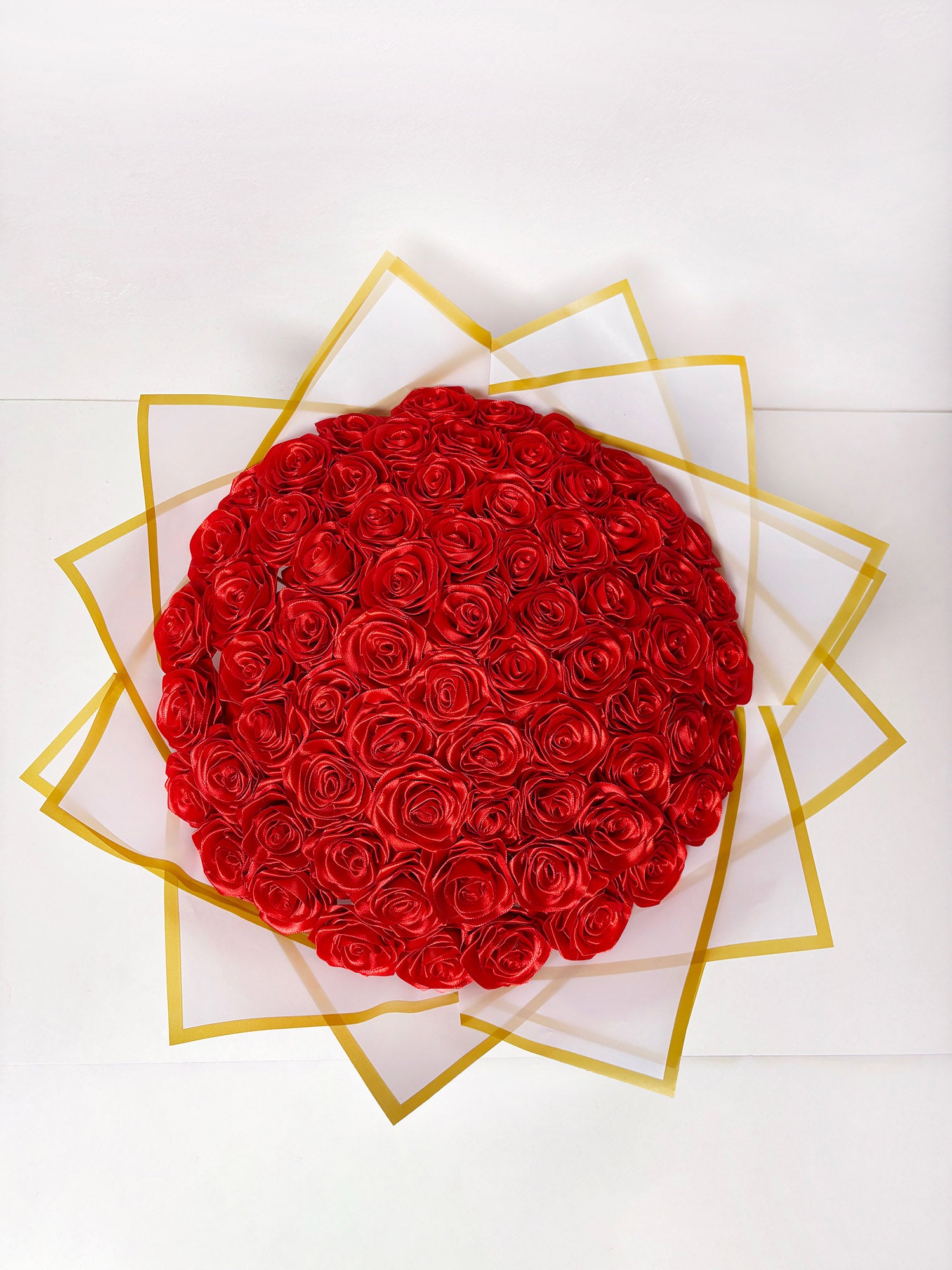 Satenast šopek vrtnic, v rdeči barvi, 70 vrtnic, ovite v bel papir z zlato obrobo
