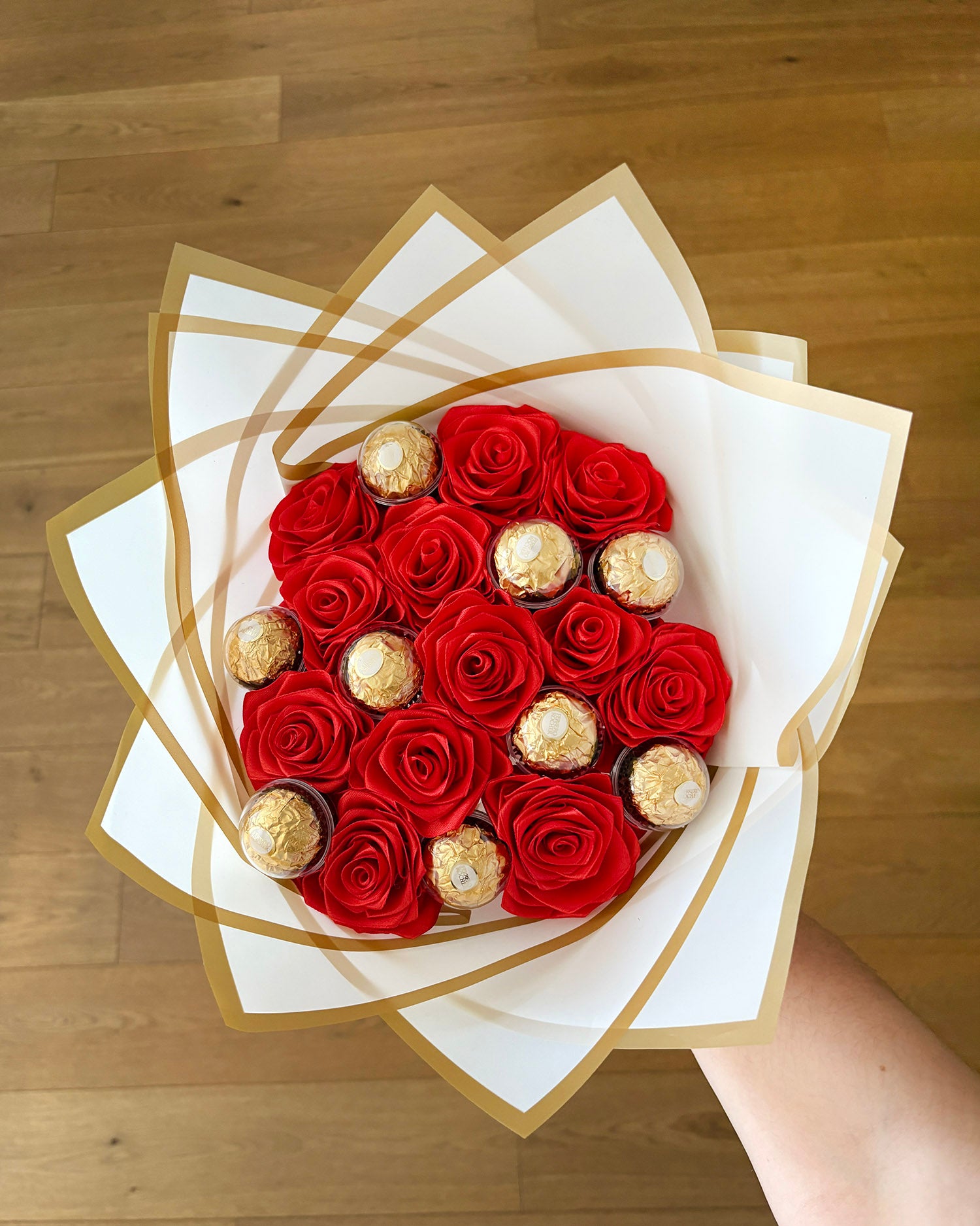 Rdeč šopek iz satenastih vrtnic slikan od zgoraj, z dodatkom ferrero roscheja
