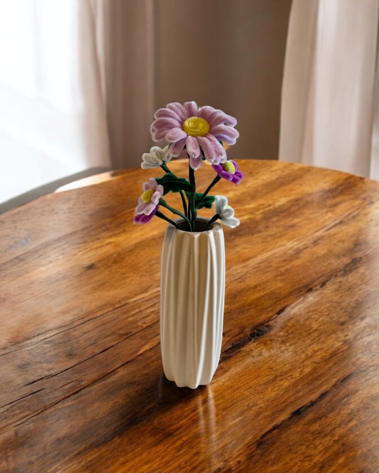 Šopek iz ksomatih žičk od zgoraj, v beli vazi na leseni mizi.