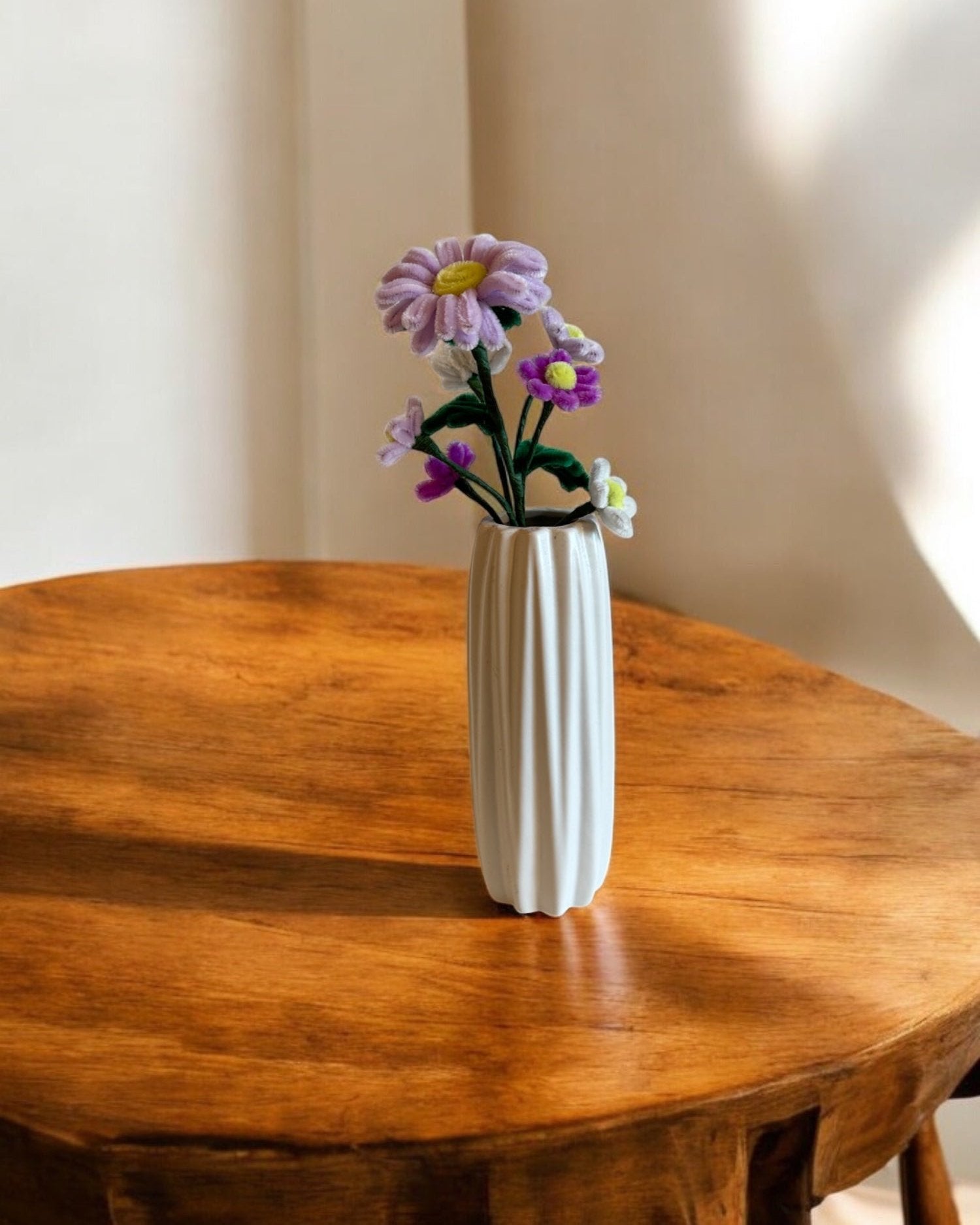 Šopek iz kosmatih žičko, v beli vazi na leseni mizi.