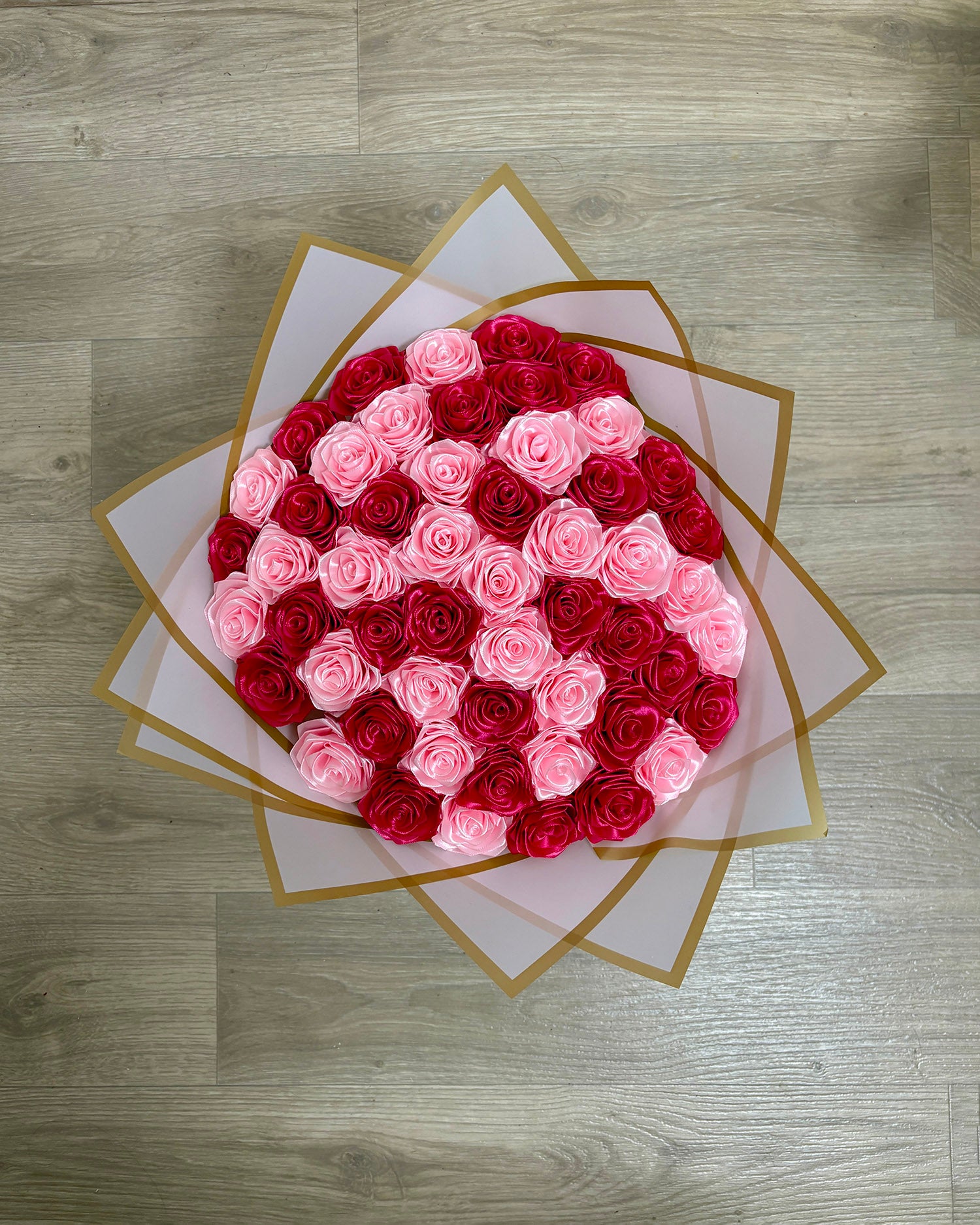 Satenast šopek vrtnic v temno roza in svetlo roza barvi, zavit v bel korejski papir, slika od zgoraj