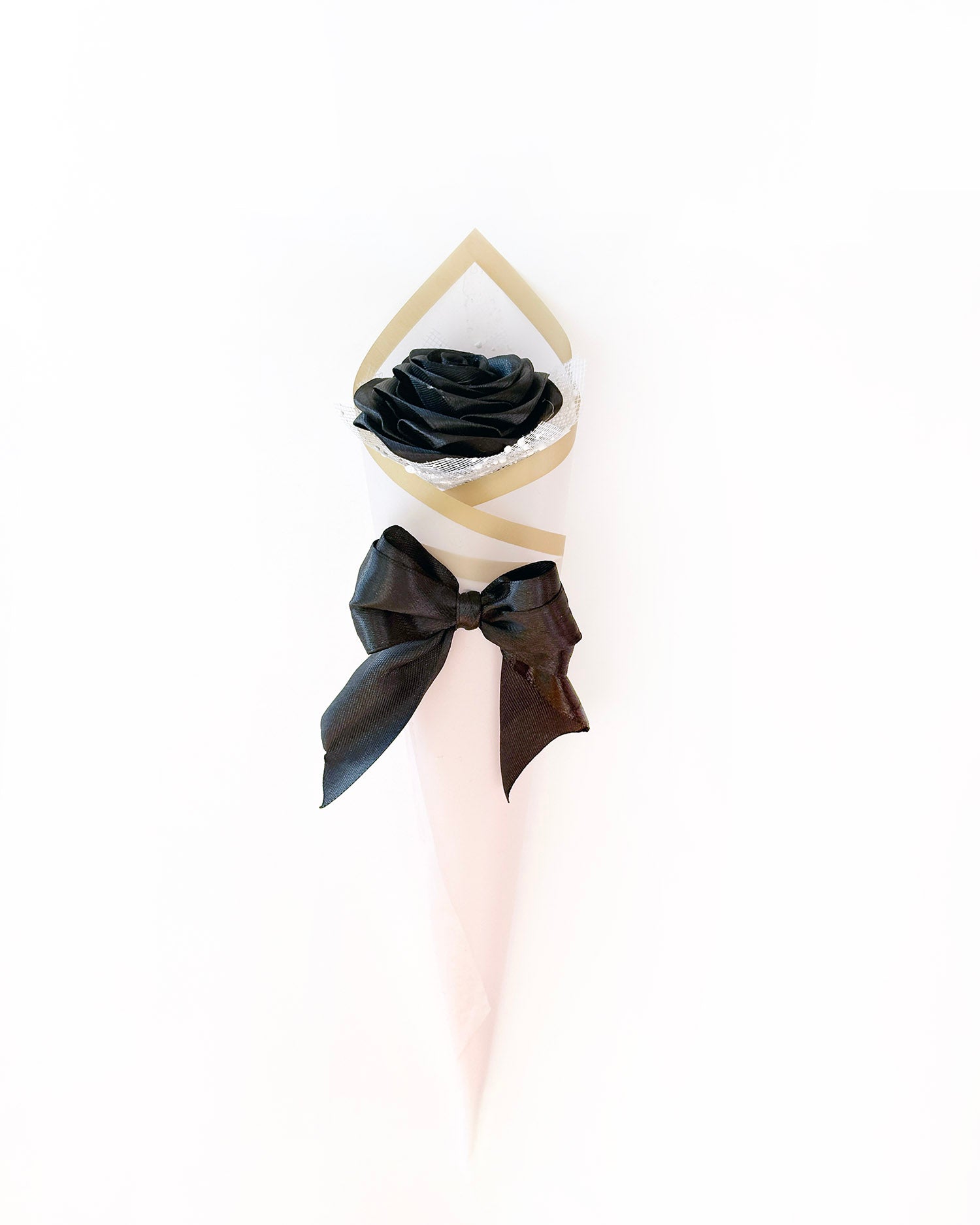 Satenasta vrtnica v črni barvi, ovita v roza korejski papir, na beli podlagi
