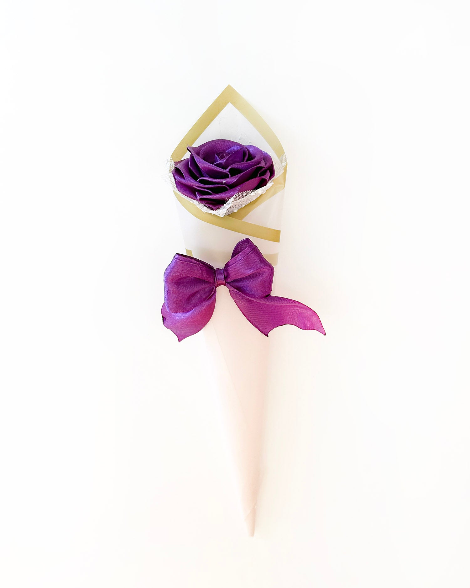 Satenasta vrtnica v vijolični barvi, ovita v roza korejski papir, na beli podlagi
