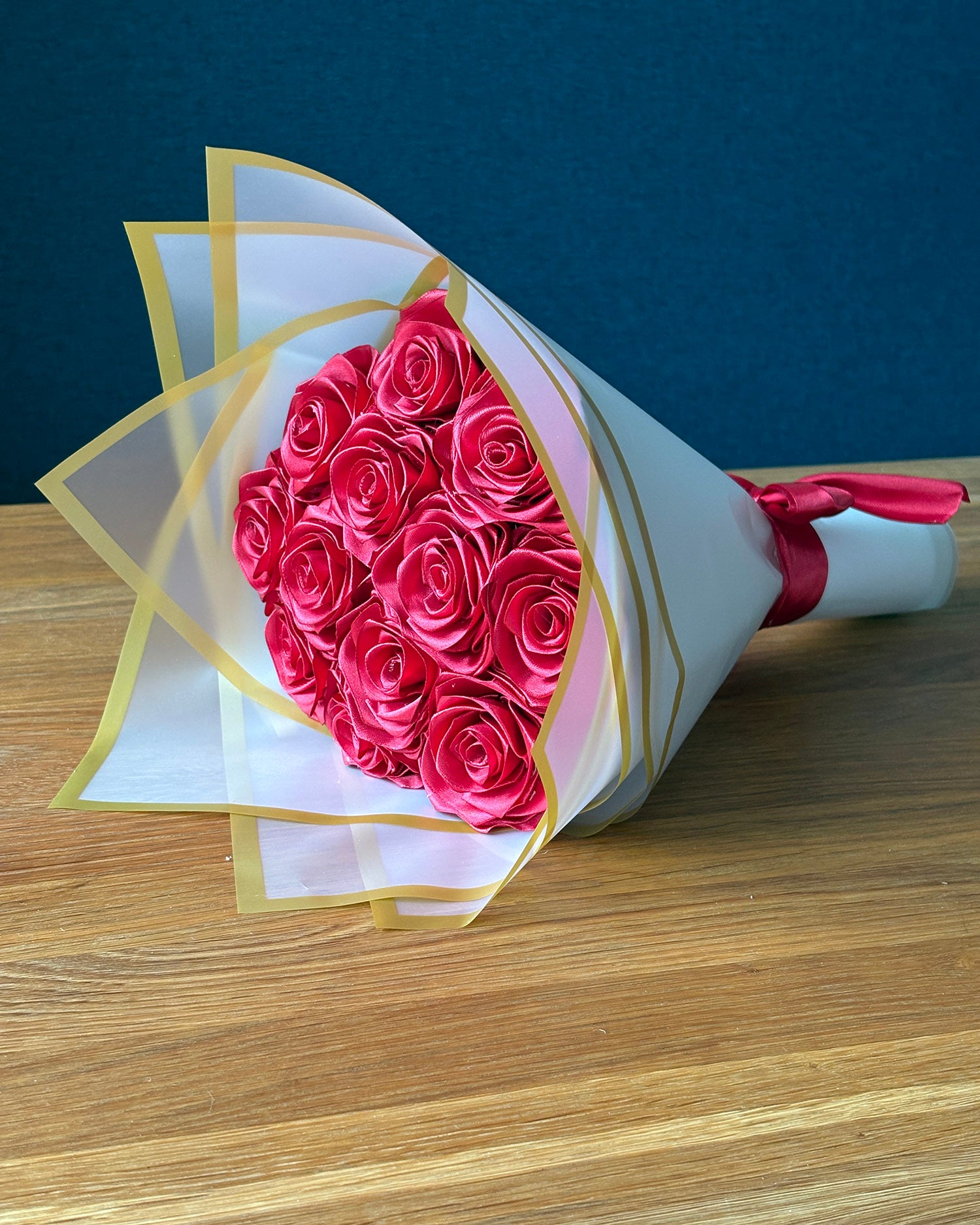 Satenski šopek rož v bordo rdeči barvi na mizi

