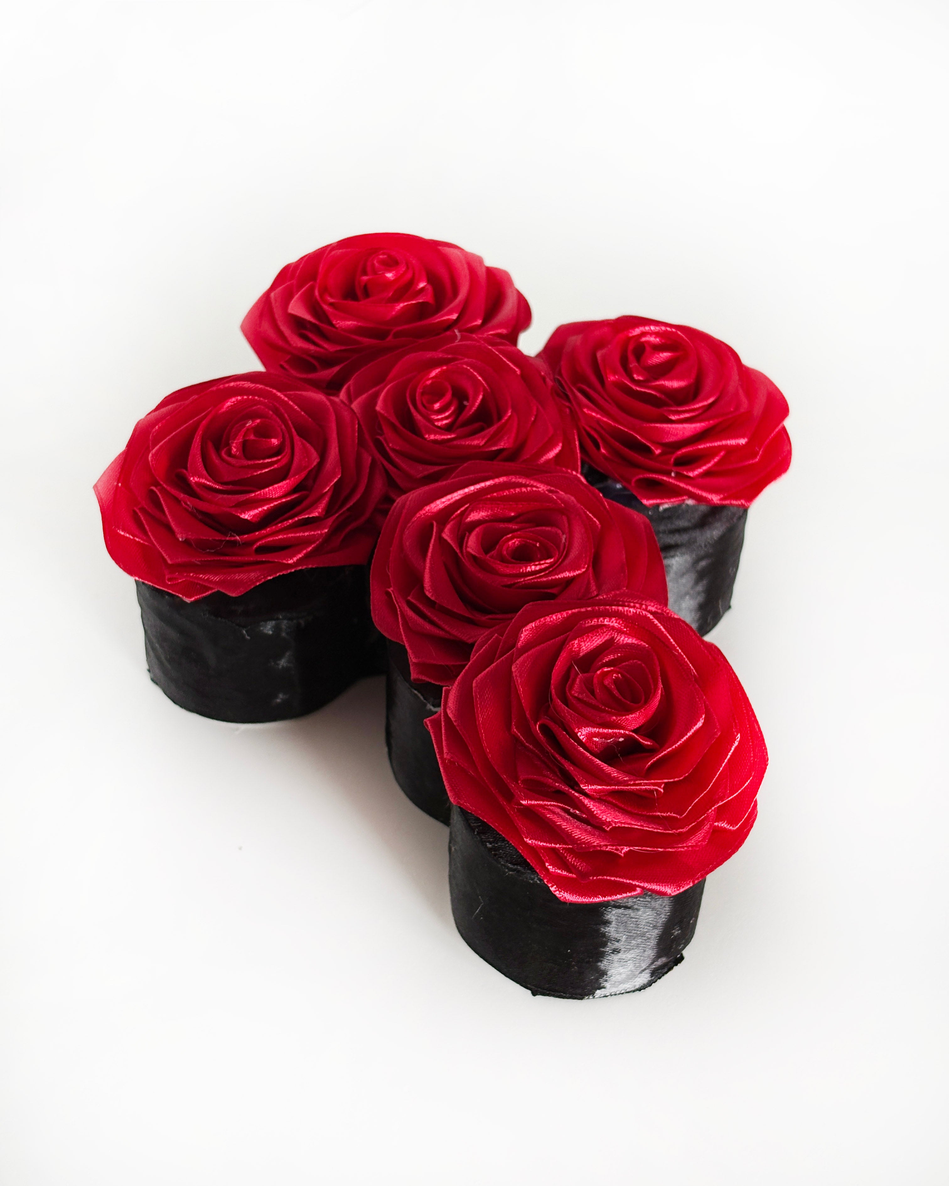 Križ iz satenastih vrtnic v bordo rdeči barvi,, slikan od strani
